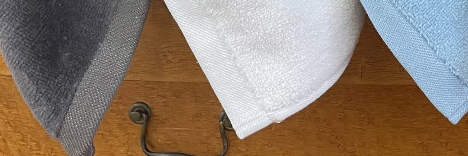 American Blanket Company - 100% Cotton Towels - Made in the usa Cotton towels - three colors of cotton towels draped over a dresser, in gray, white, and blue.