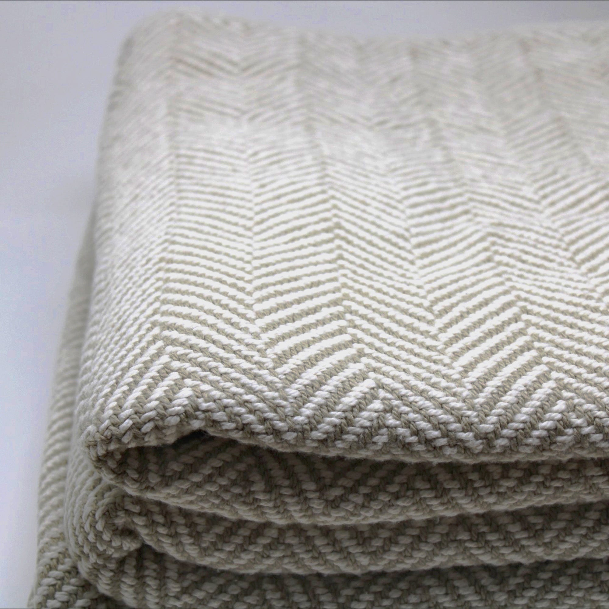 American Blanket Company - 100% Cotton Bed Blanket, Feather Weave  cotton Pattern Blanket - Close up of the woven herringbone cotton blanket in khaki and white, showing the tight knit construction of the pattern.