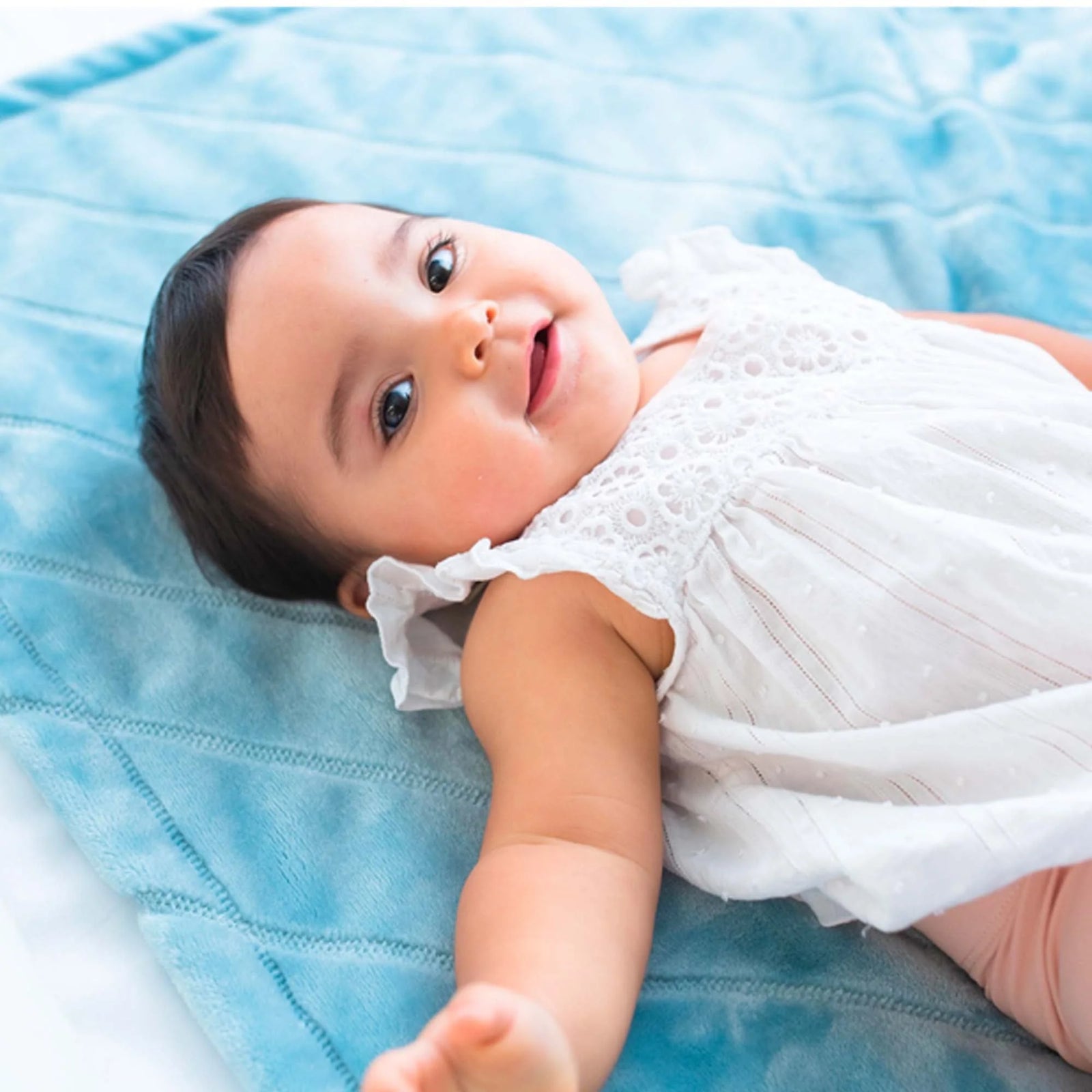 AMERICAN BLANKET COMPANY - FLEECE BABY BLANKETS - A BABY LYING ON A FLEECE LUSTER LOFT FLEECE BLANKET QUILT SMILING UP AT THE CAMERA