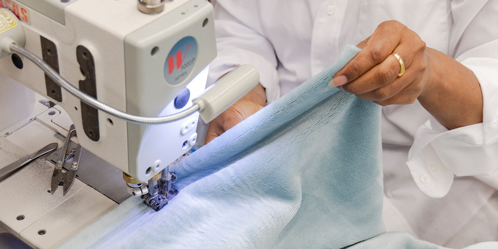 American blanket company - Luster Loft Fleece fleece Blanket - Person using a sewing machine sewing a luster loft fleece blanket