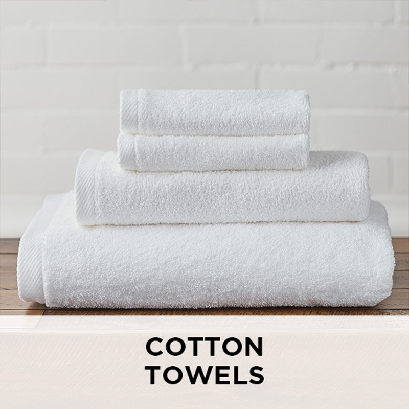 AMERICAN BLANKET COMPANY - 100% COTTON TOWELS - NEATLY FOLDED CRISP WHITE COTTON TOWELS ON A WOODEN TRUNK.