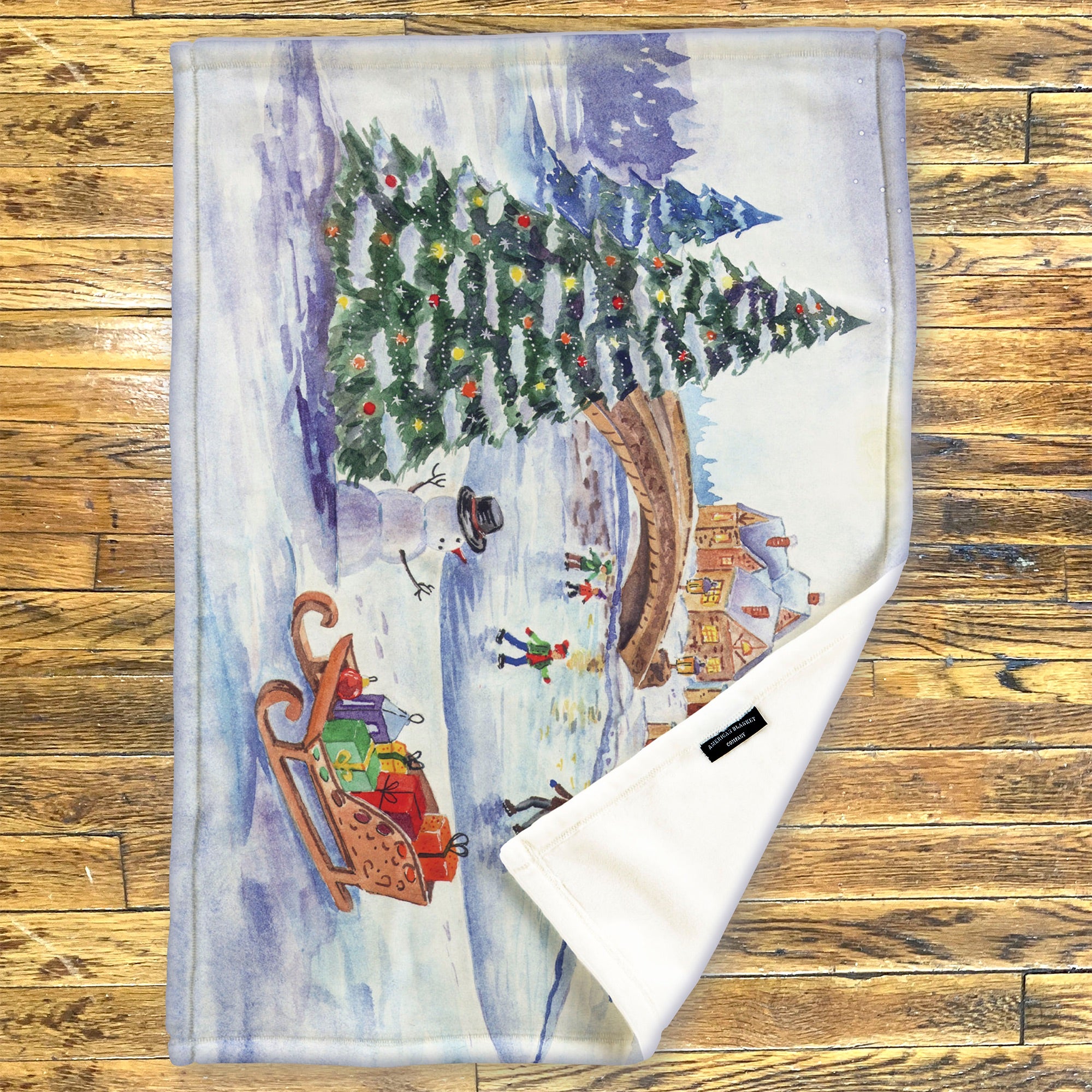 American Blanket Company - Luster Loft Fleece Blanket - Printed Holiday Throw Blanket - Fleece blanket with a winter scene featuring a Christmas tree, sleigh, and village on a wooden surface.