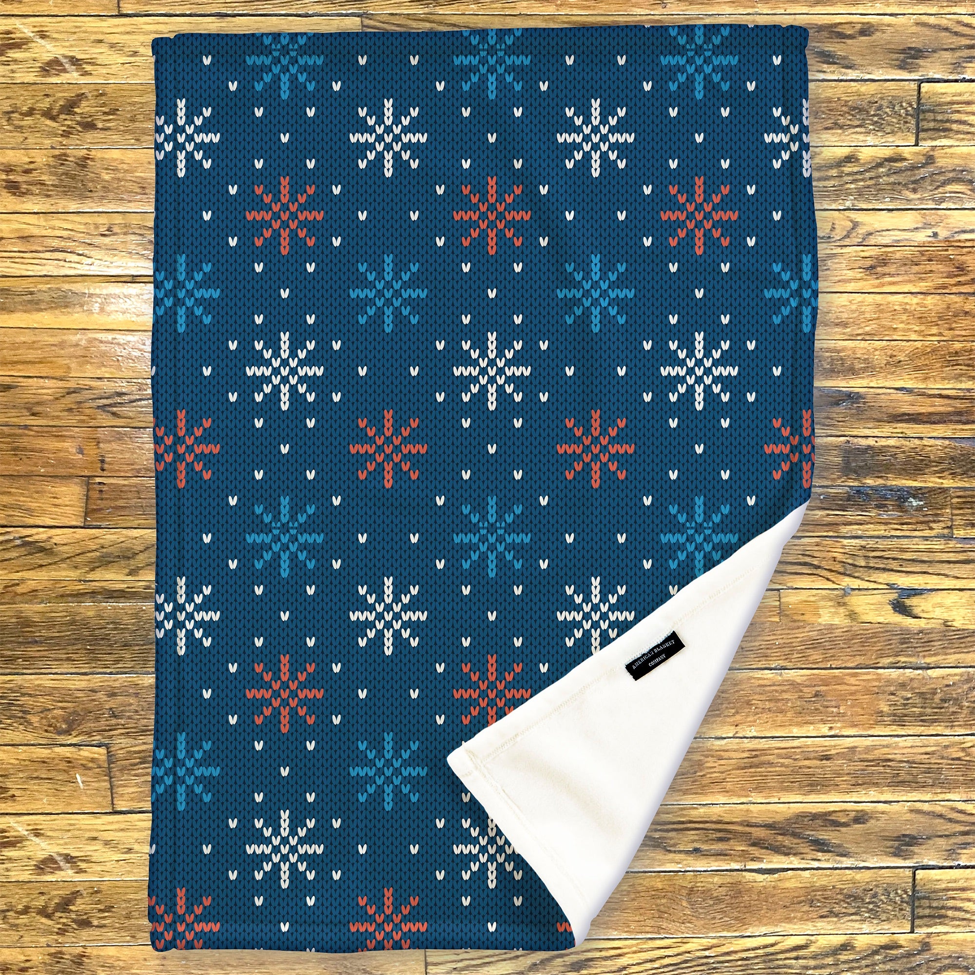 American Blanket Company - Luster Loft Fleece Blanket - Printed Holiday Throw Blanket - fleece blanket with snowflake pattern on a wooden surface