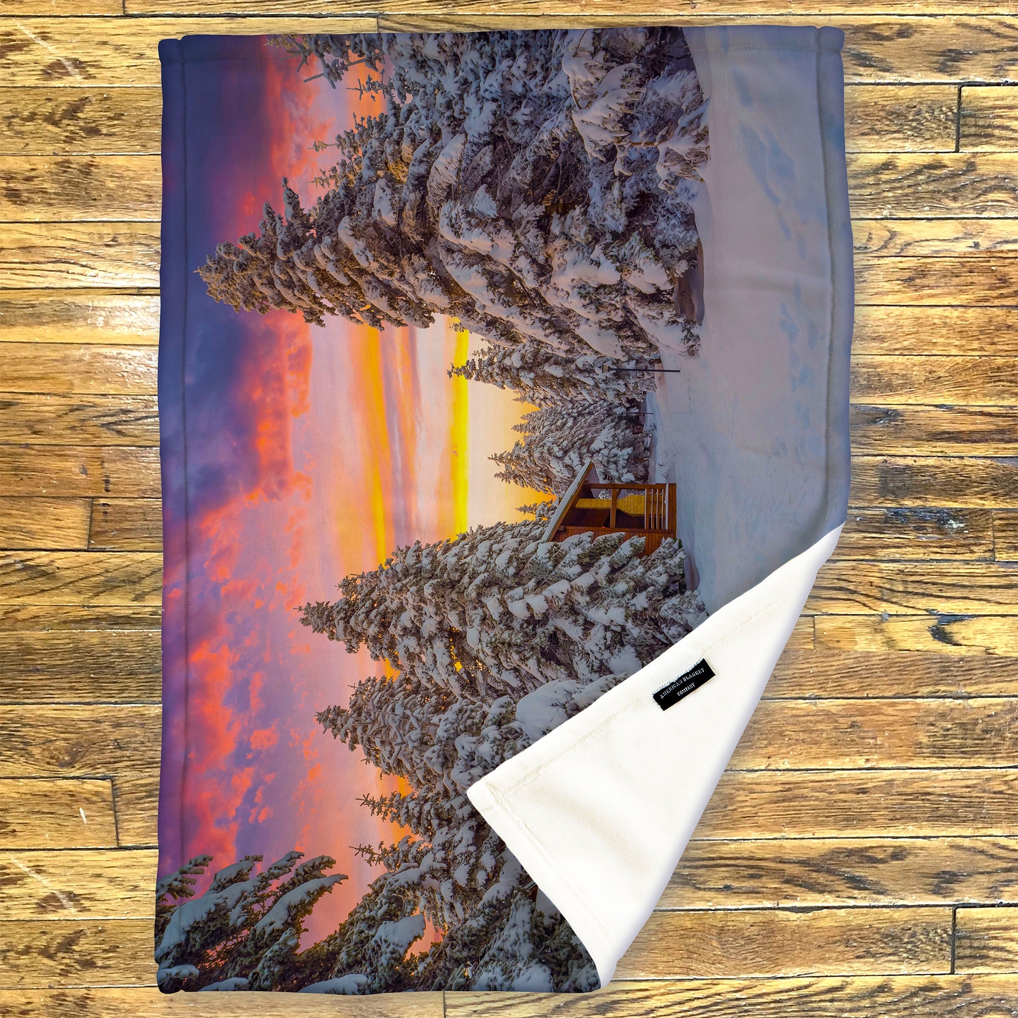 American Blanket Company - Luster Loft Fleece Blanket - Printed Holiday Throw Blanket - Fleece blanket with a winter landscape design featuring trees and a sunset on a wooden surface.