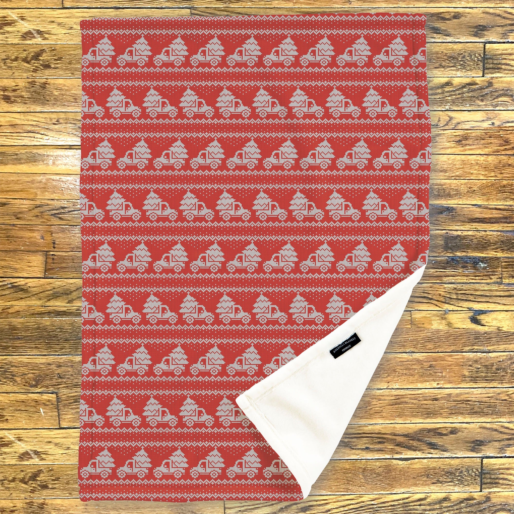American Blanket Company - Luster Loft Fleece Blanket - Printed Holiday Throw Blanket - Red and white patterned rug with a white triangle on a wooden background