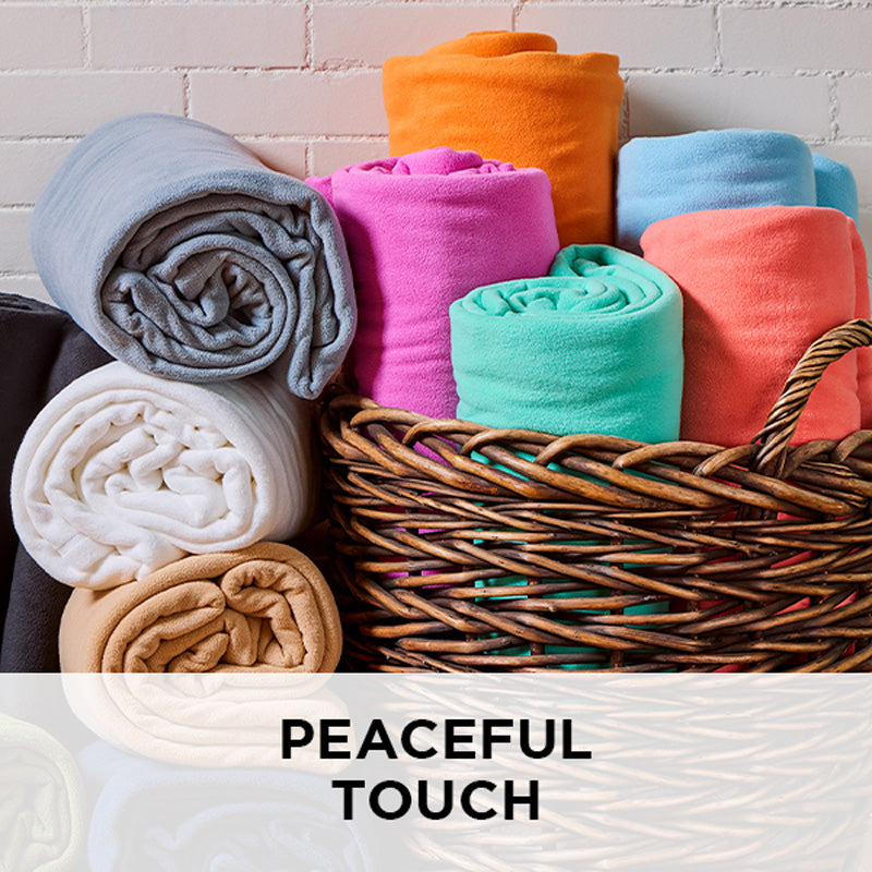 AMERICAN BLANKET COMPANY - PEACEFUL TOUCH FLEECE BLANKETS - COLORFUL ROLLS OF PEACEFUL TOUCH  FLEECE BLANKETS FALLING OUT OF A BASKET
