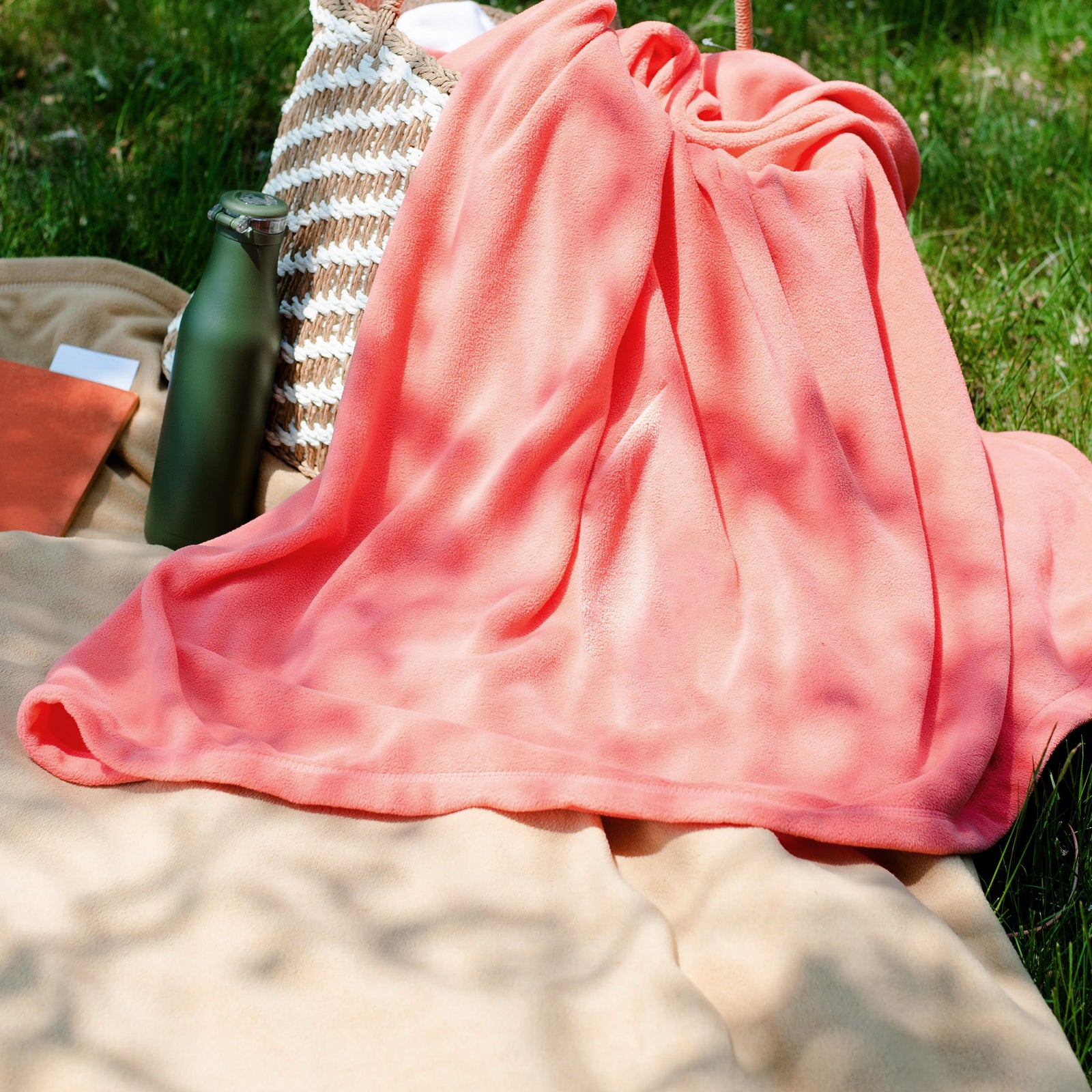 American Blanket Company - Peaceful Touch Fleece Blankets - Coral pink fleece blanket on the grass for a picnic