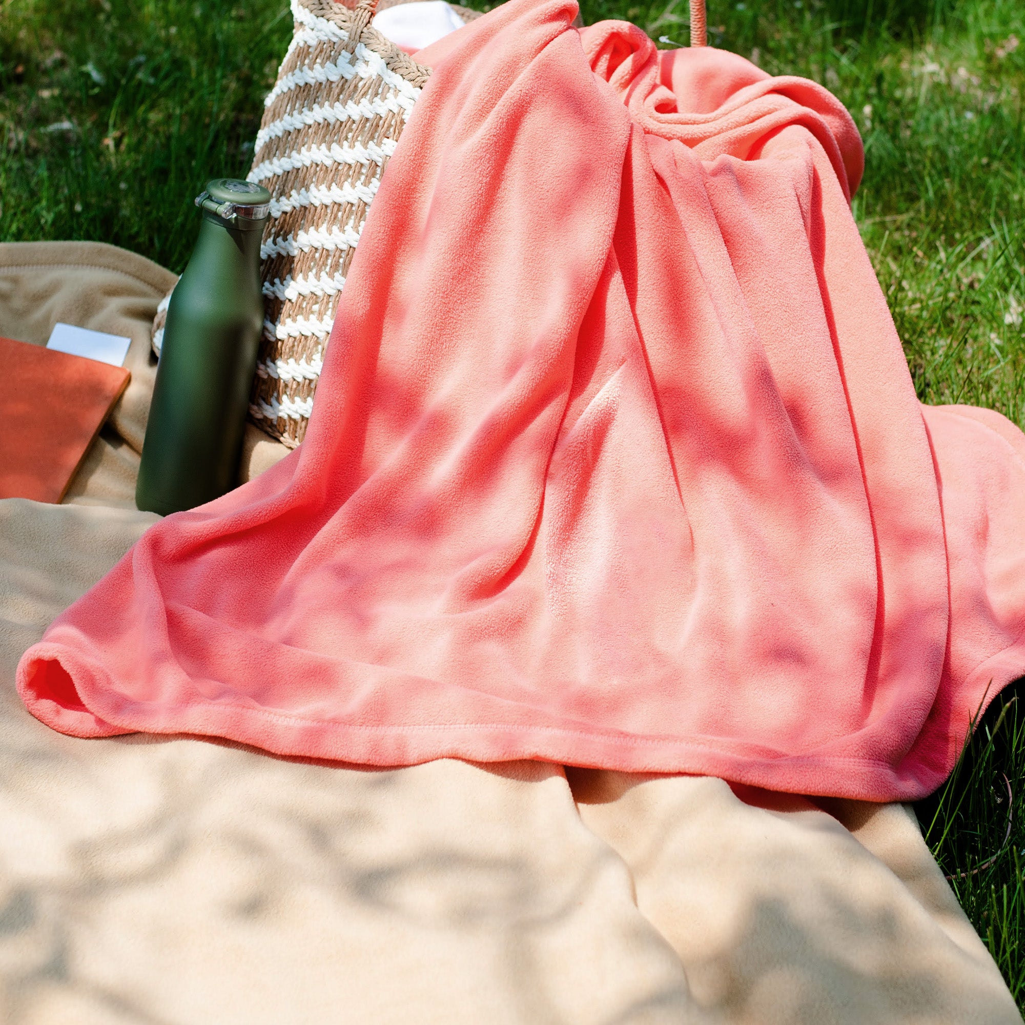American Blanket Company - Peaceful Touch Fleece Blankets - Coral pink fleece blanket on the grass for a picnic