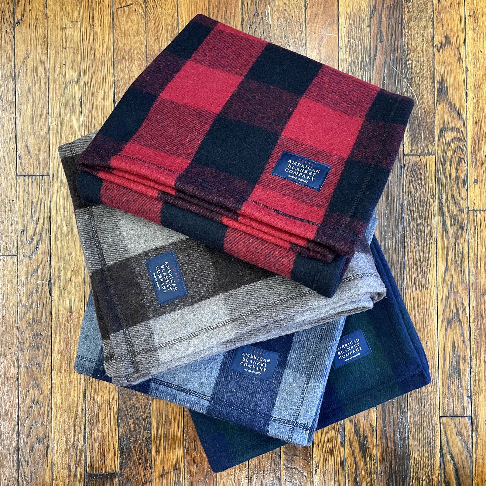 American Blanket Company - Recycled Wool Blankets - Stack of red, gray, blue, and green plaid wool blankets