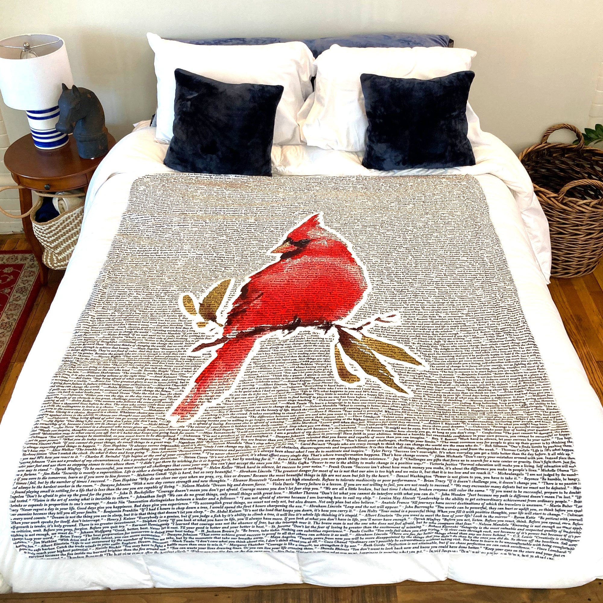 American Blanket Company - Cardinal Printed inspirational quote blanket - A vibrant Cardinal printed blanket laying on a cozy bed featuring quotes from many famous writers, philosophers, and the like.
