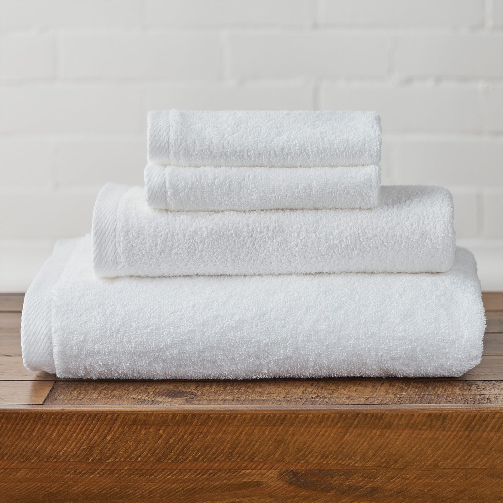 AMERICAN BLANKET COMPANY - 100% COTTON BATH TOWELS - NEATLY FOLDED CRISP WHITE 100% COTTON TOWELS ON A WOODEN TRUNK.
