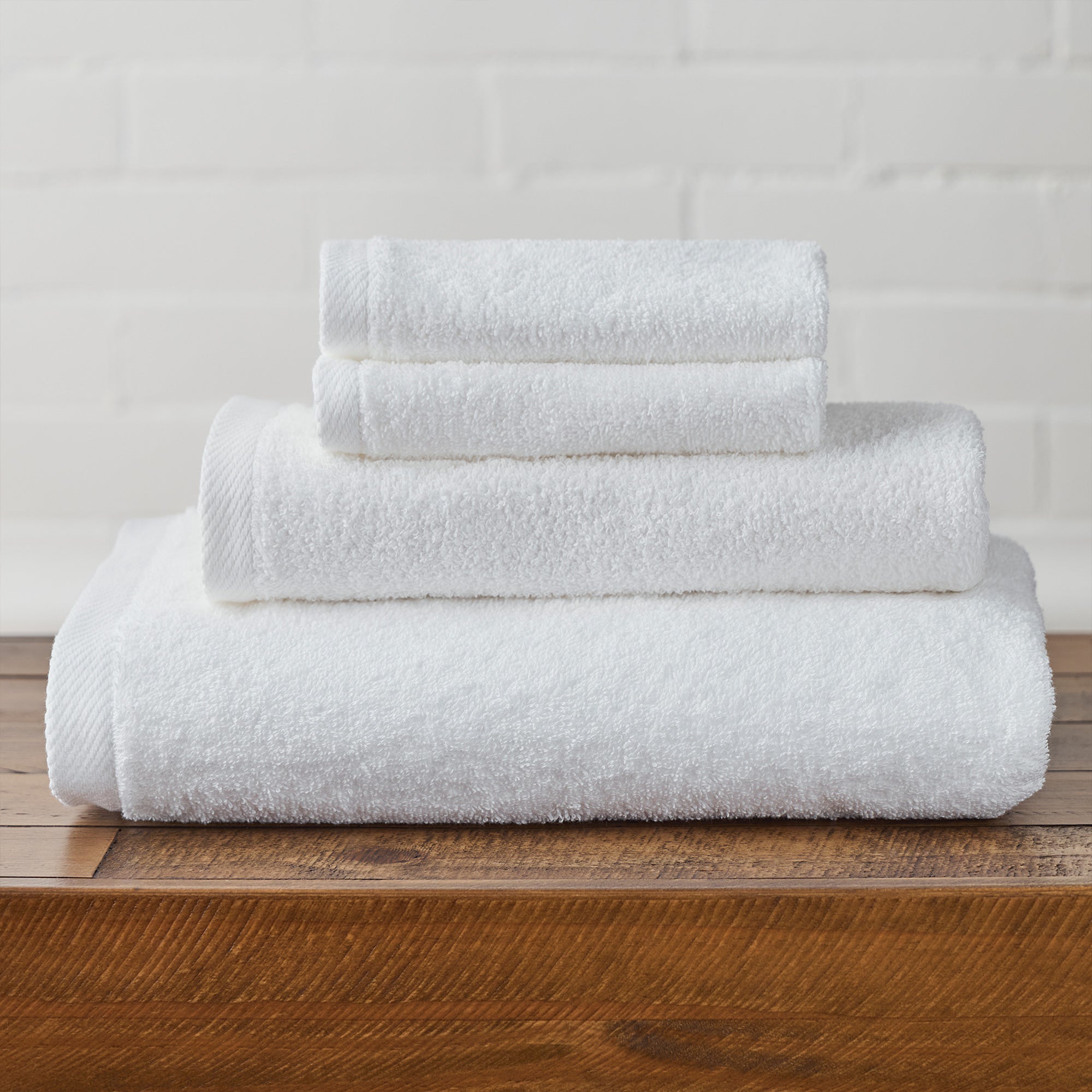 AMERICAN BLANKET COMPANY - 100% COTTON BATH TOWELS - NEATLY FOLDED CRISP WHITE 100% COTTON TOWELS ON A WOODEN TRUNK.