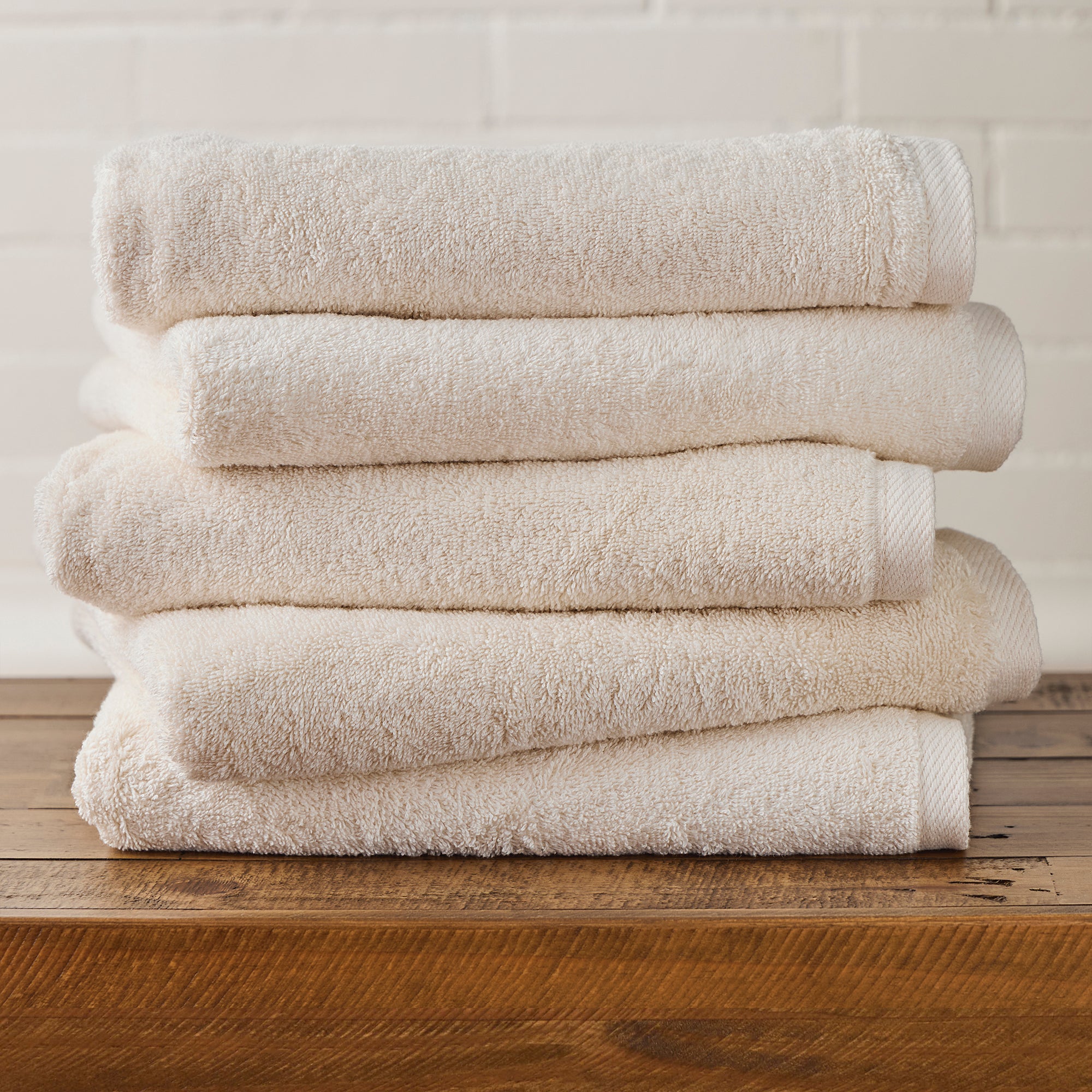 AMERICAN BLANKET COMPANY - 100% COTTON BATH TOWELS - NEATLY FOLDED CRISP BEIGE 100% COTTON TOWELS ON A WOODEN TRUNK.