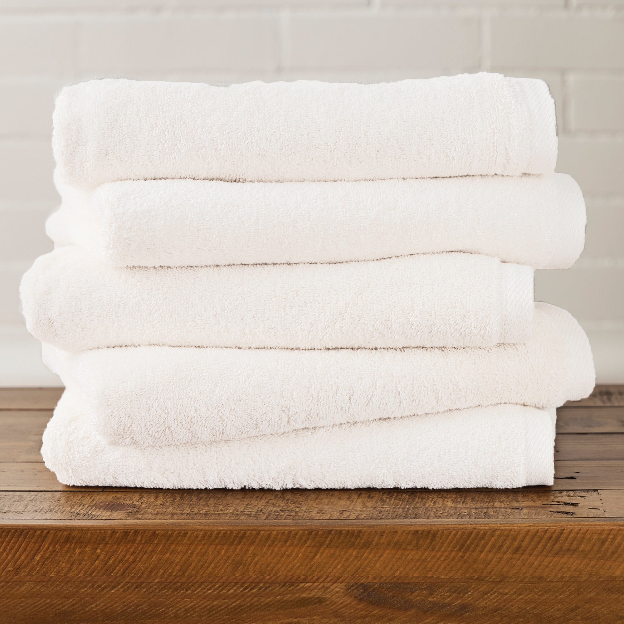 AMERICAN BLANKET COMPANY - 100% COTTON BATH TOWELS  - Stack of white 100% cotton towels on a wooden surface with a neutral background