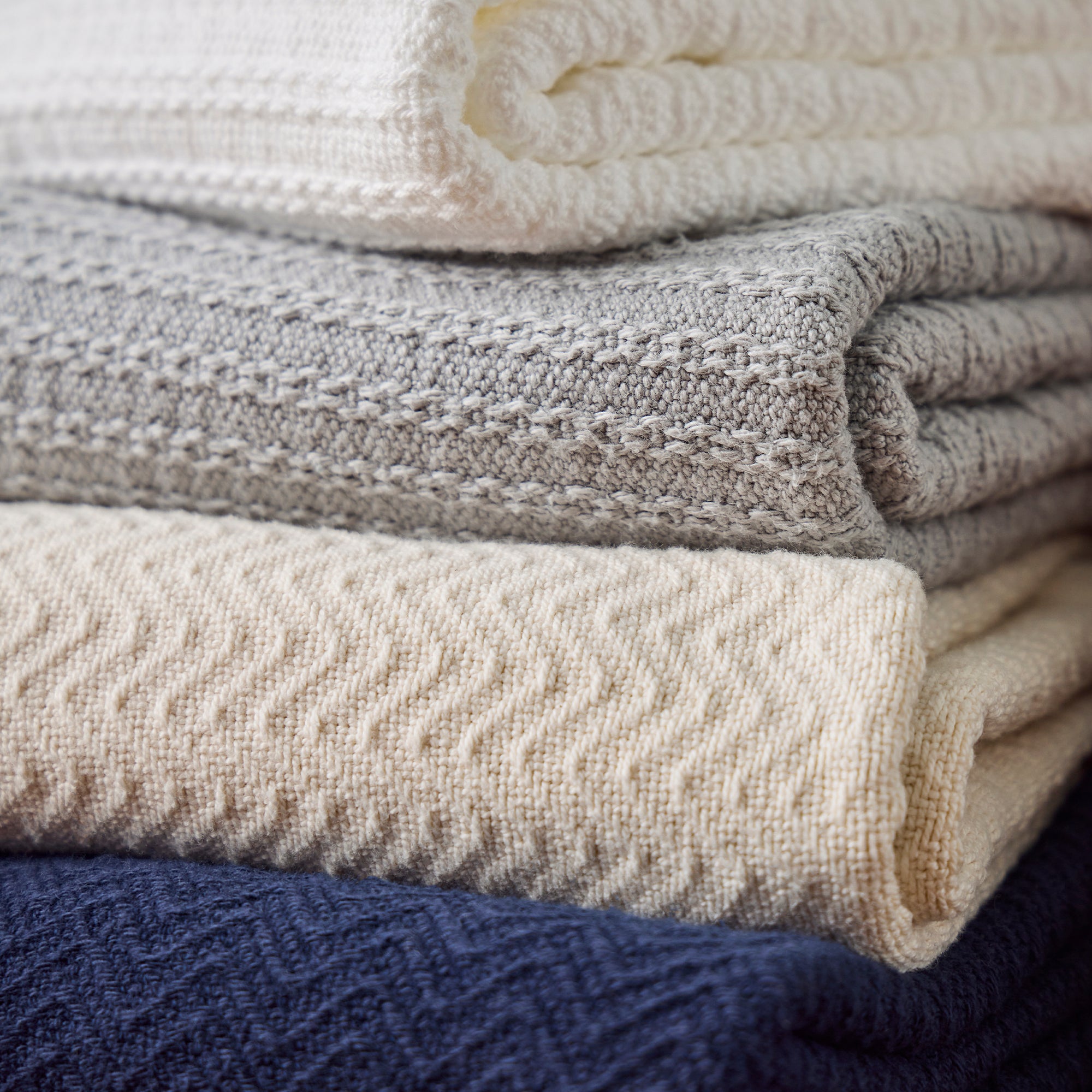 American Blanket Company - Oversized Cable weave 100% Cotton Blanket - Stack of folded 100% Cotton Blankets in various colors and weaves