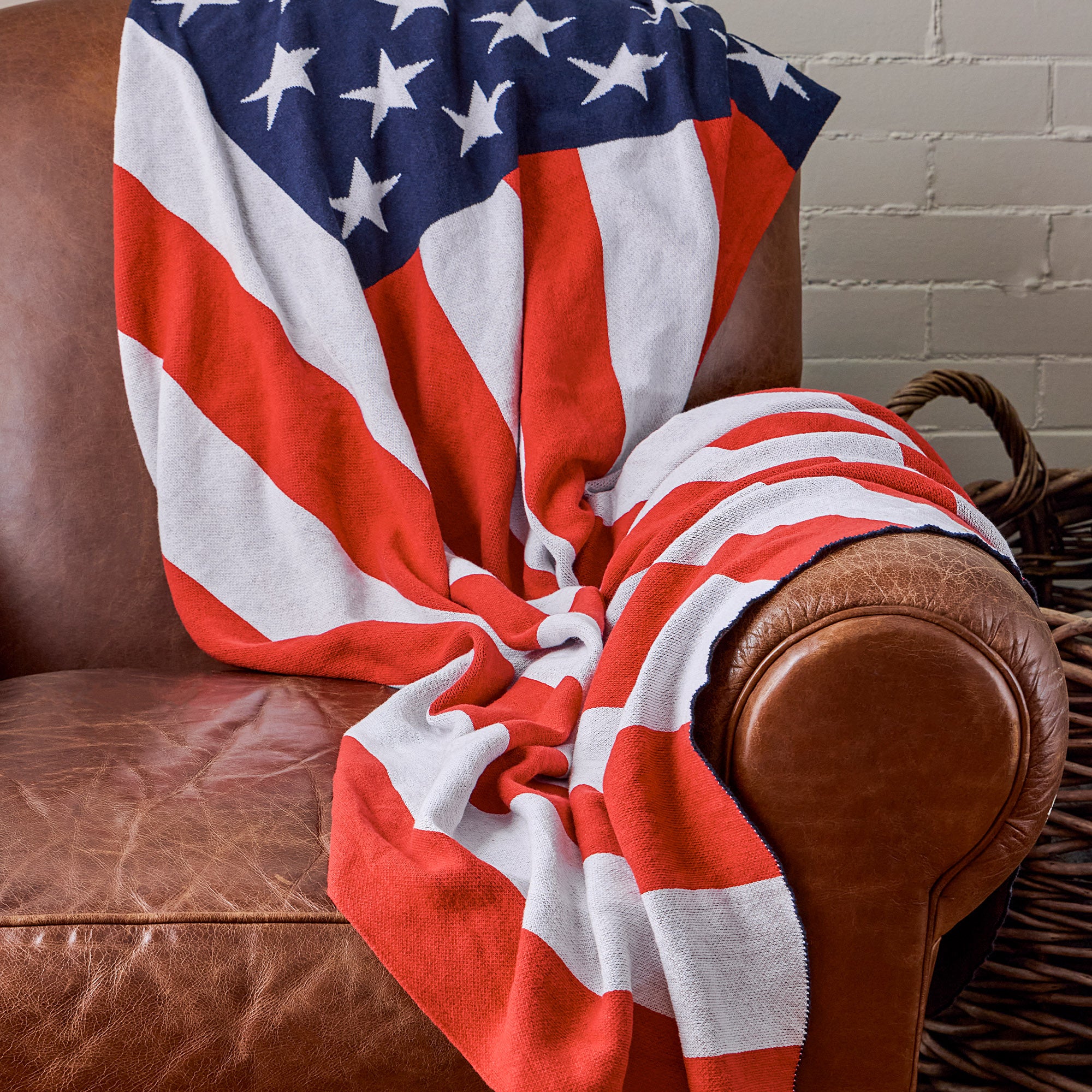 AMERICAN BLANKET COMPANY - KNITTED FLAG BLANKETS - A KNITTED AMERICAN FLAG BLANKET 50% Cotton 50% polyester DRAPED OVER A VINTAGE LIGHT LEATHER ARMCHAIR