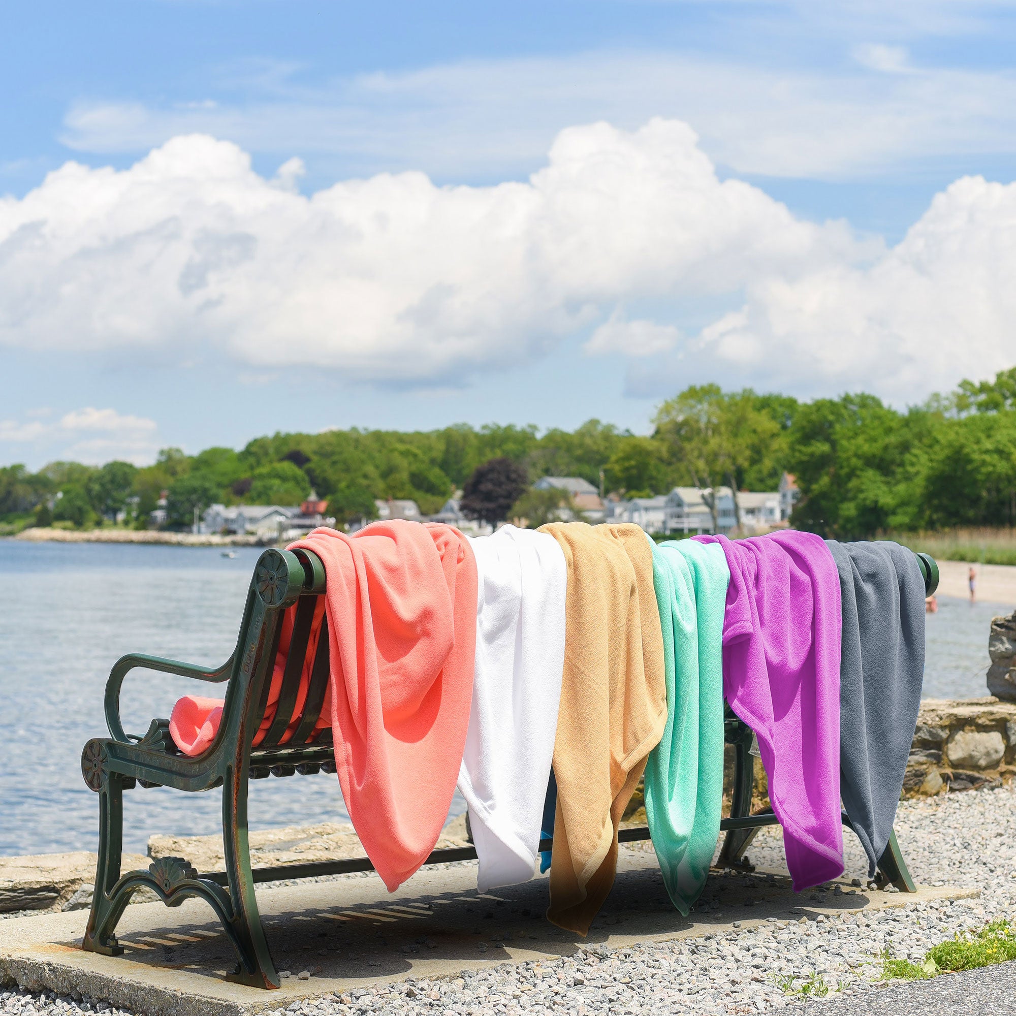 American Blanket Company - Peaceful Touch Fleece Blankets - Assorted fleece blankets on a bench out lookout onto a beach