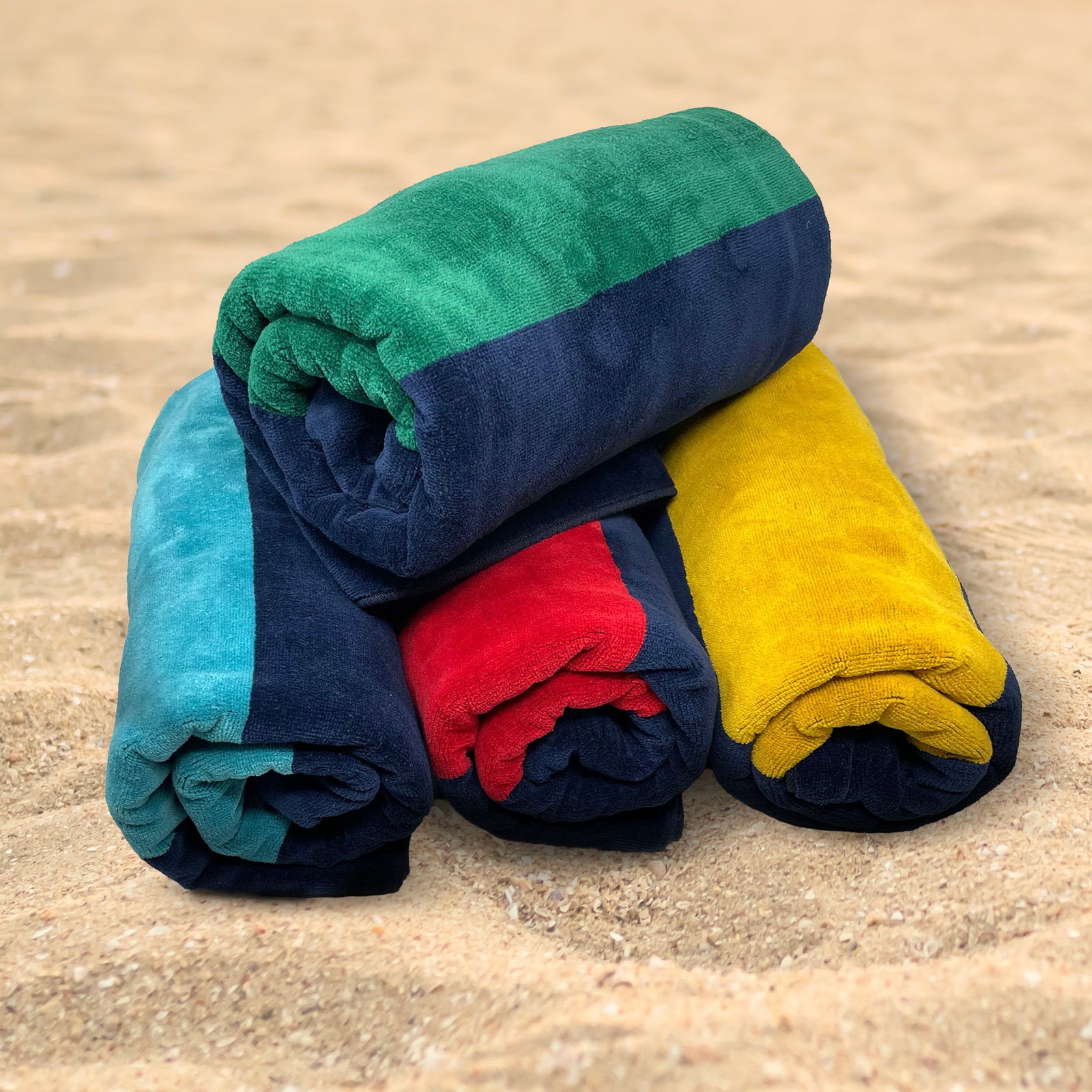 American Blanket Company - Rugby Stripe 100% Cotton Beach Towels - stack of 4 rugby cotton towels in assorted color on a sandy background.