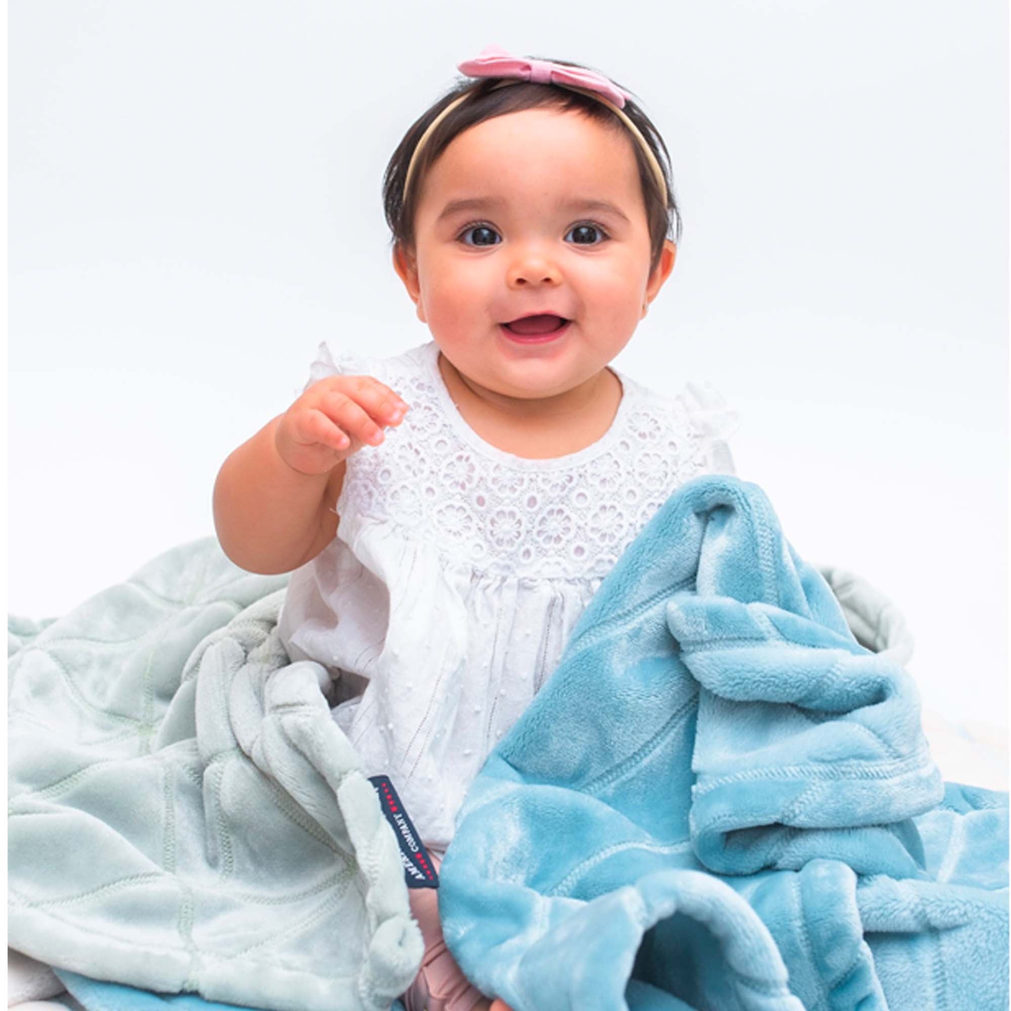 American Blanket Company - Luster Loft Baby Blanket - Birch on Luster Loft Fleece  in buxton blue and cotton ball with a small smiling baby wrapped in both.