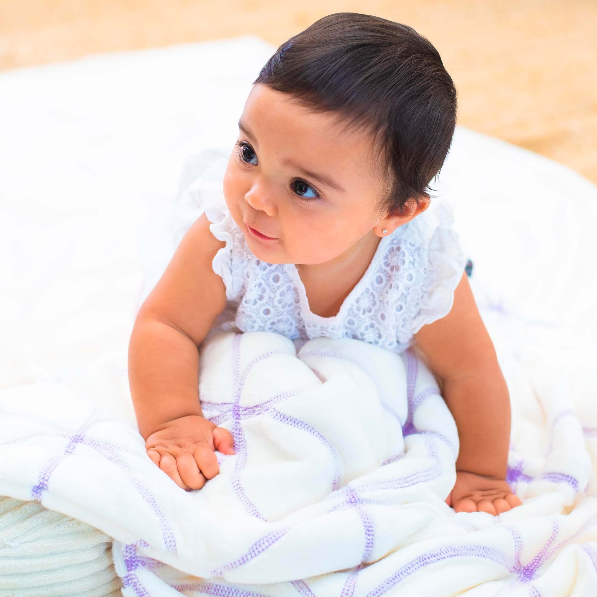 American Blanket Company - Luster Loft Baby Blanket Quilt- Gardenia on Luster Loft Fleece with a smiling baby crawling on a lilac embroidered luster loft cotton ball quilt.