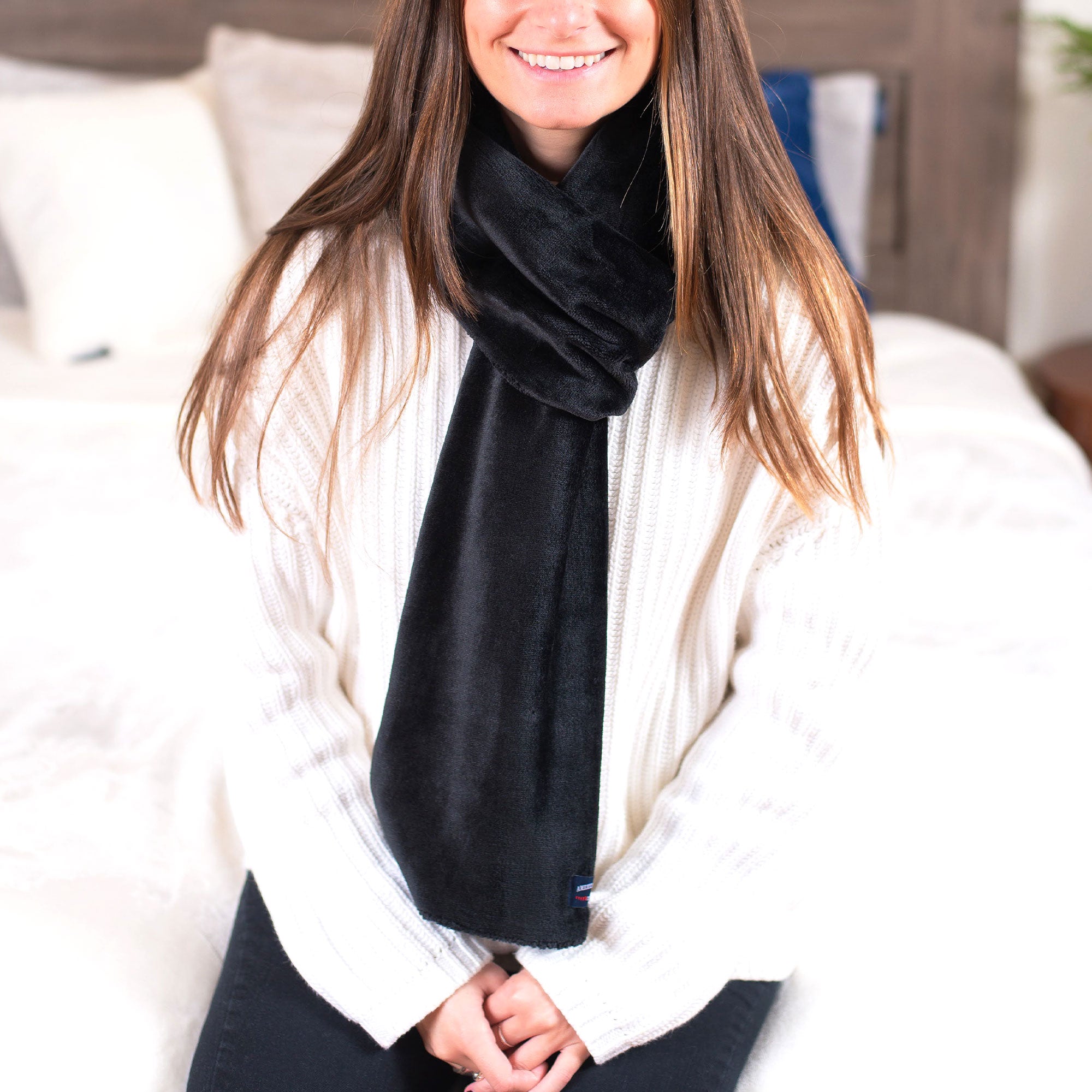 American Blanket Company - Luster Loft Fleece Scarf - Young woman sitting on bed wearing black luster loft fleece scarf 