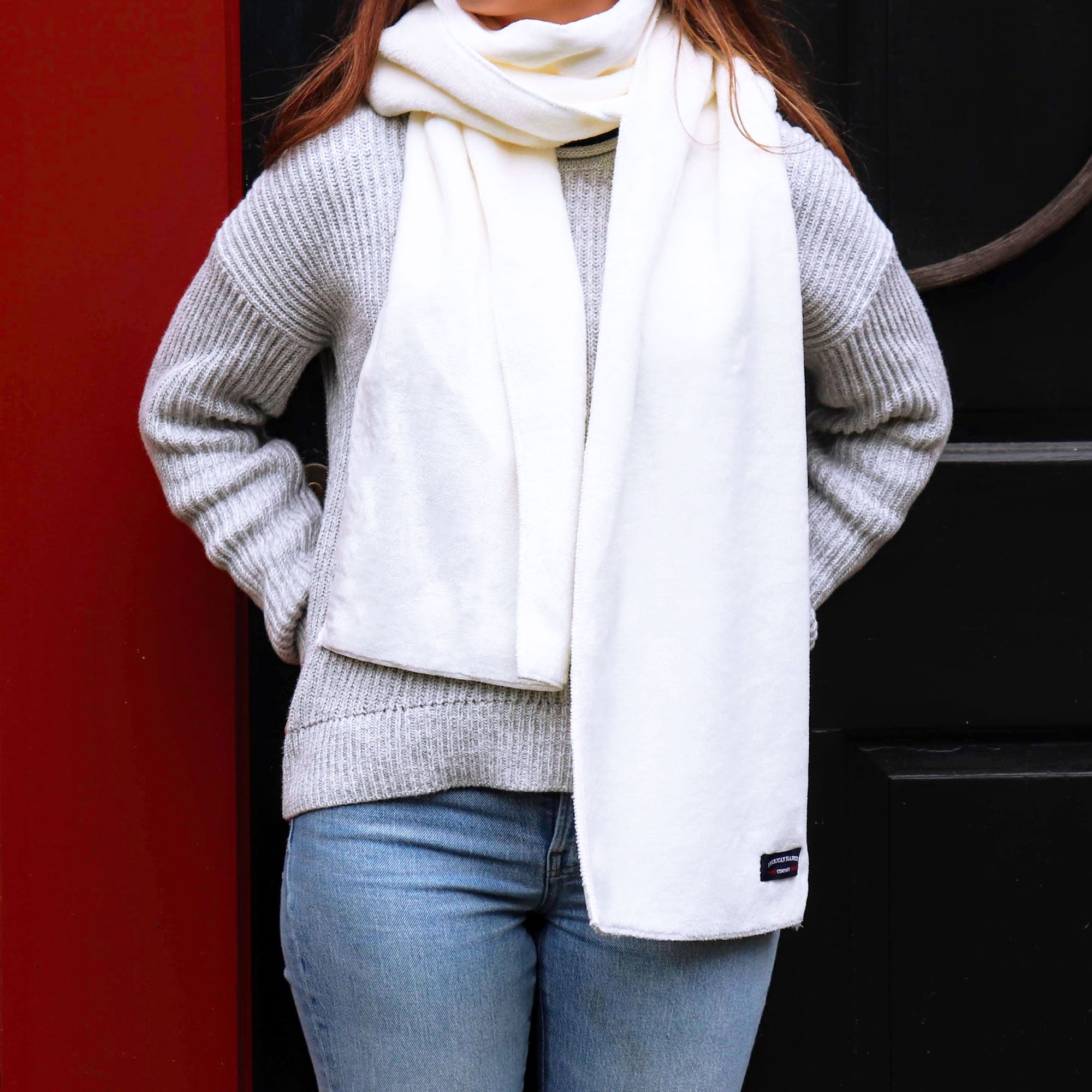 American Blanket Company - Luster Loft Fleece Scarf - Young woman wearing luster loft fleece scarf  in front of a dark red front door.
