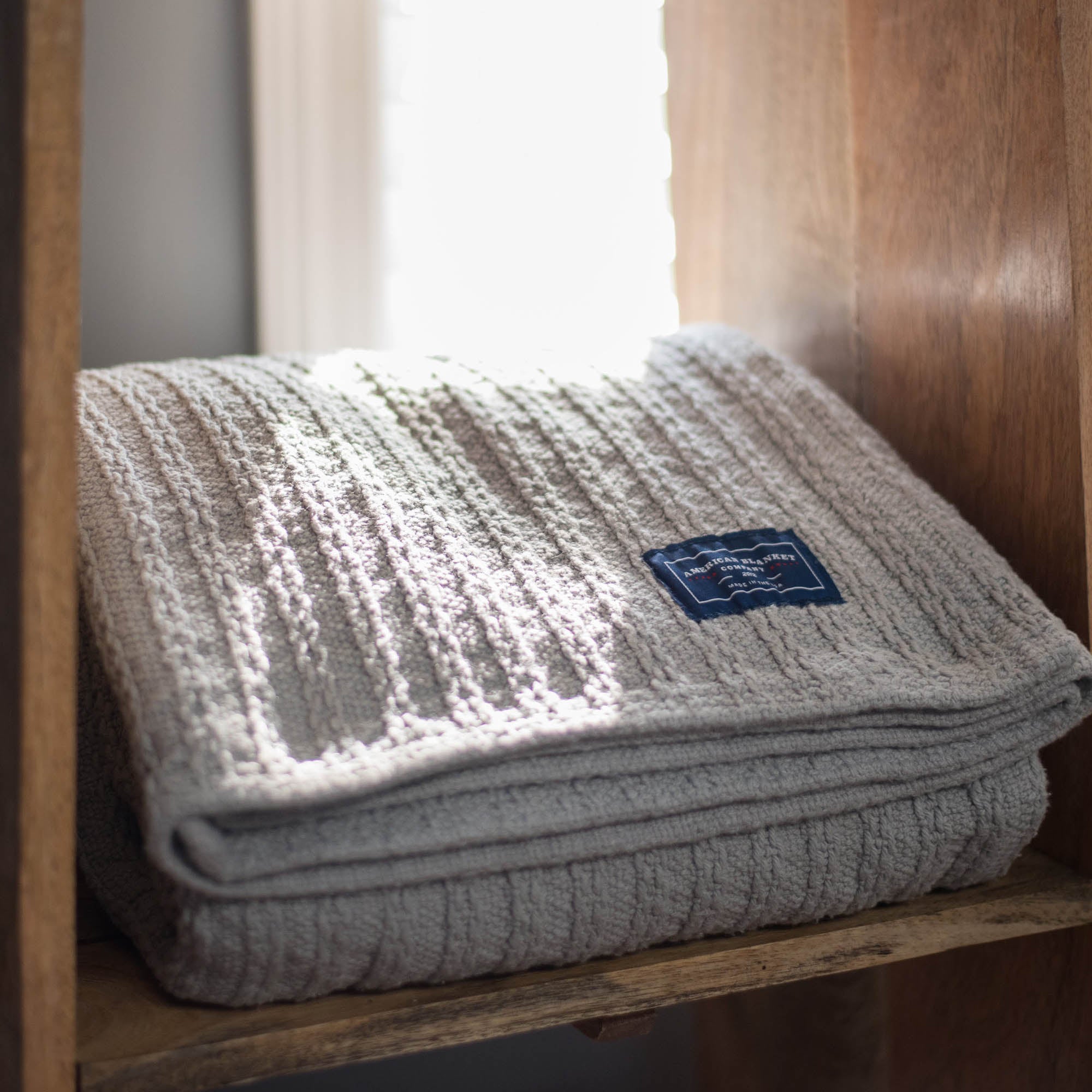 American Blanket Company - Oversized Cable weave 100% Cotton Blanket - gray colored cable weave blanket on a shelf